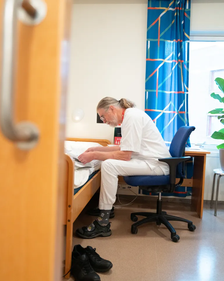 Mann i sykepleieruniform leser