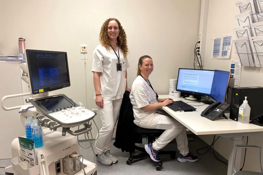 Et par kvinner i et rom med datamaskiner og utstyr