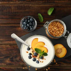 Yoghurt og gryn og frukt på et bord. Bilde.