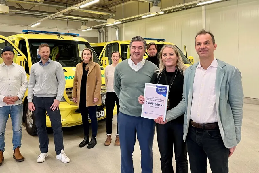 En gruppe mennesker som poserer for et bilde foran en gul lastebil