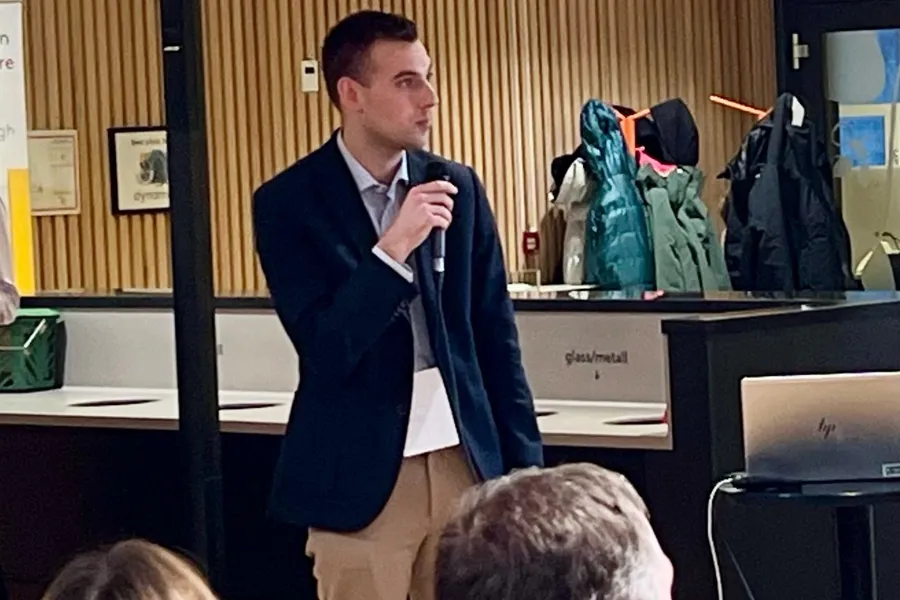 En person i dress som snakker til en gruppe mennesker