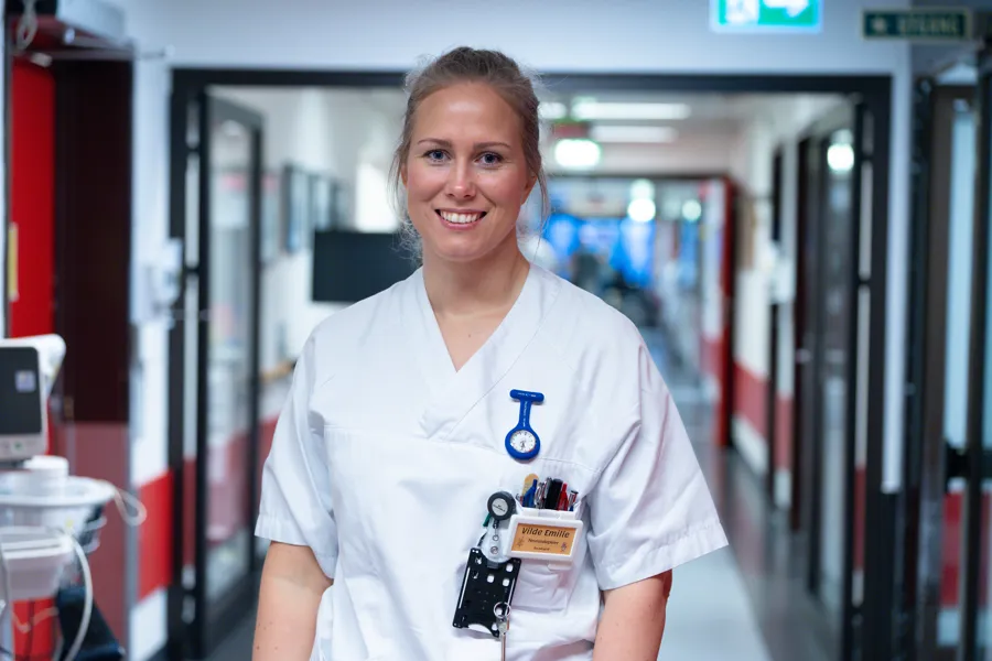 Kvinne i sykepleieruniform smiler til kamera