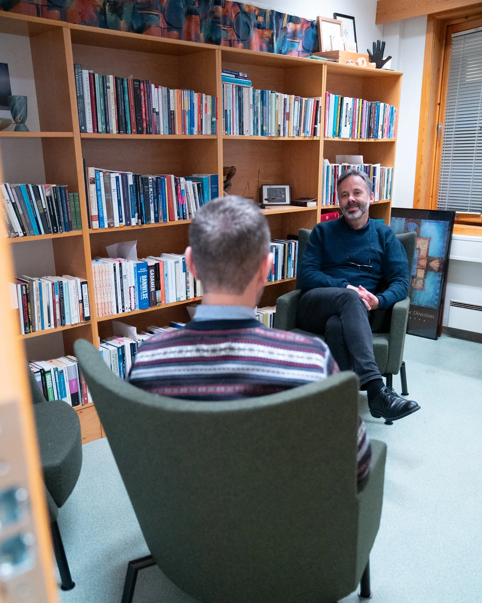 En person som sitter i en stol foran en bokhylle