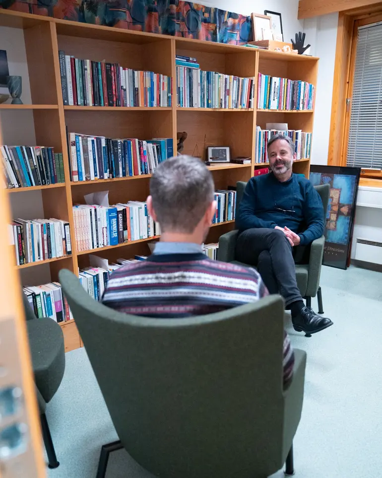 En person som sitter i en stol foran en bokhylle