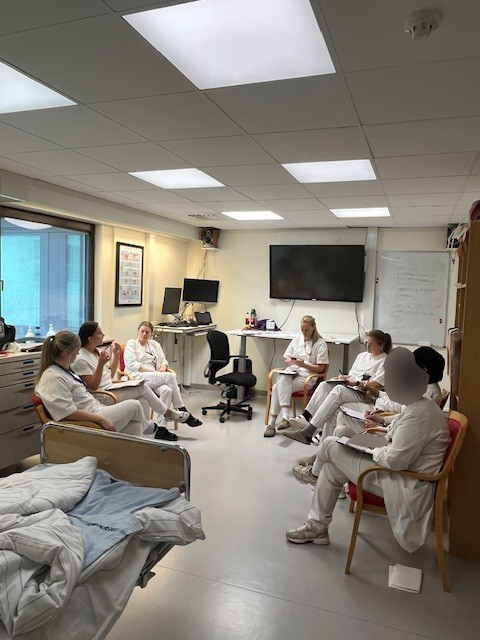 En gruppe mennesker som sitter i et rom med datamaskiner