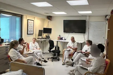 En gruppe mennesker som sitter i et rom med datamaskiner