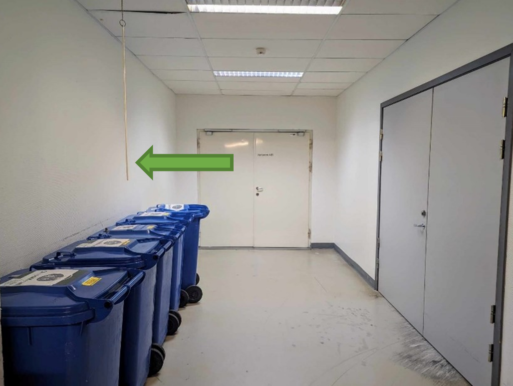 Et rom med hvite dører og blå søppelkasser