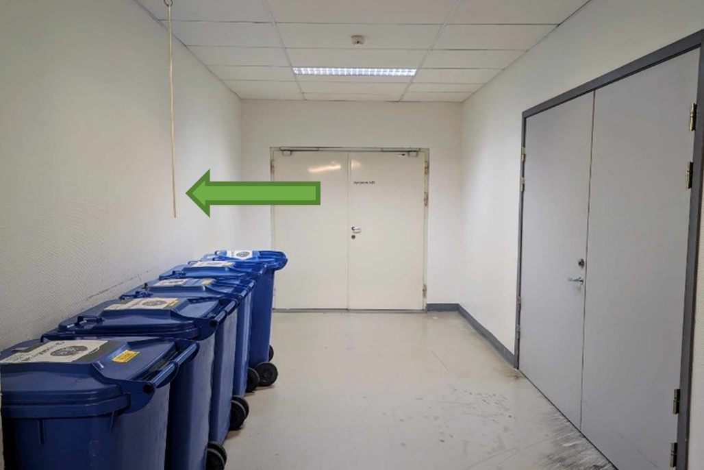 Et rom med hvite dører og blå søppelkasser