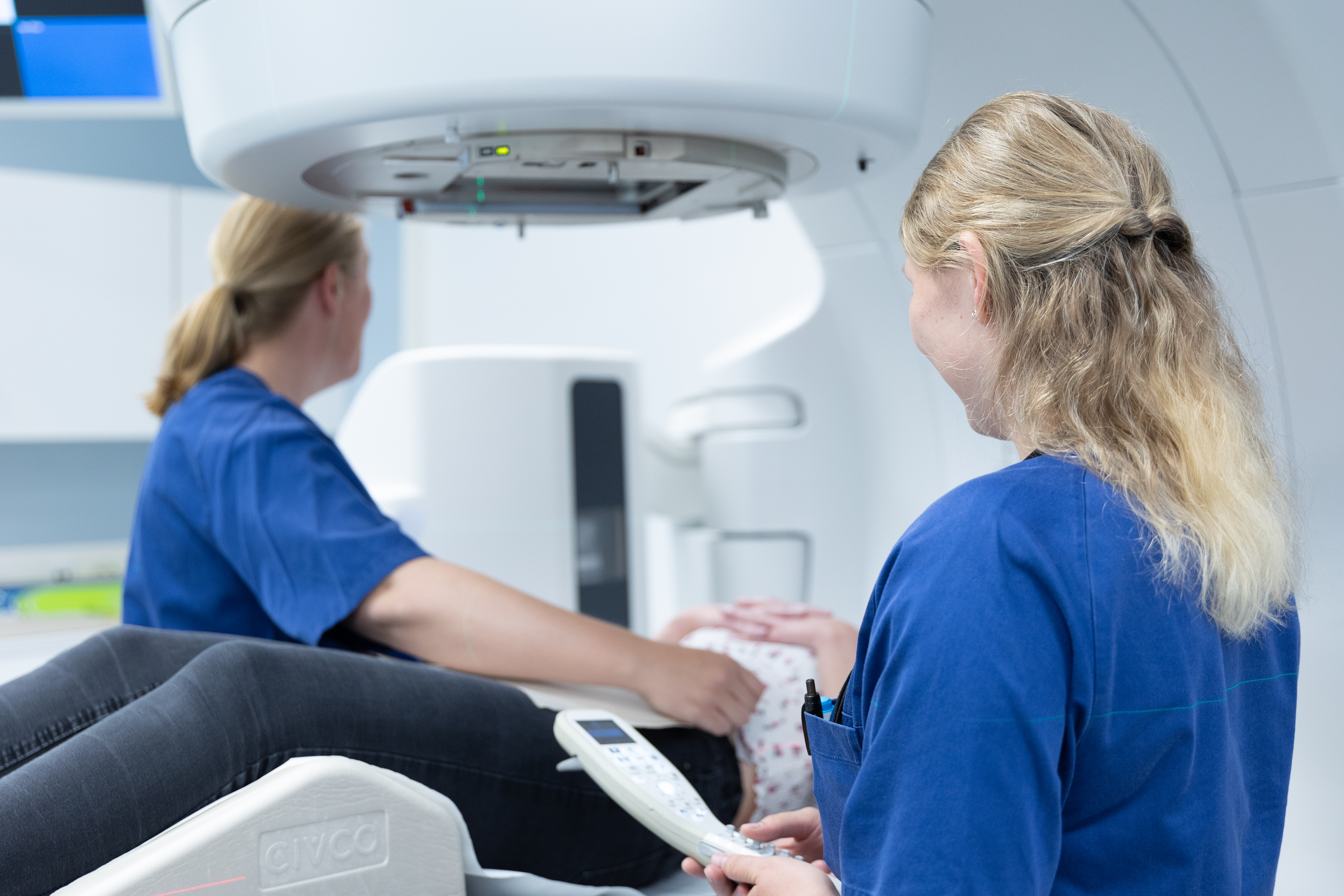 To kvinner i blå klær ved en maskin