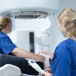 To kvinner i blå klær ved en maskin