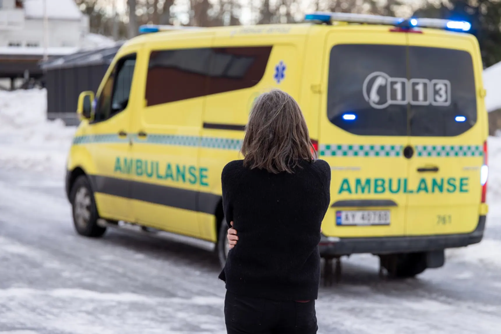 A person standing in front of a yellow van in the snow
