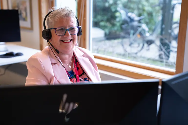 En mann med hodetelefoner og sitter ved et skrivebord