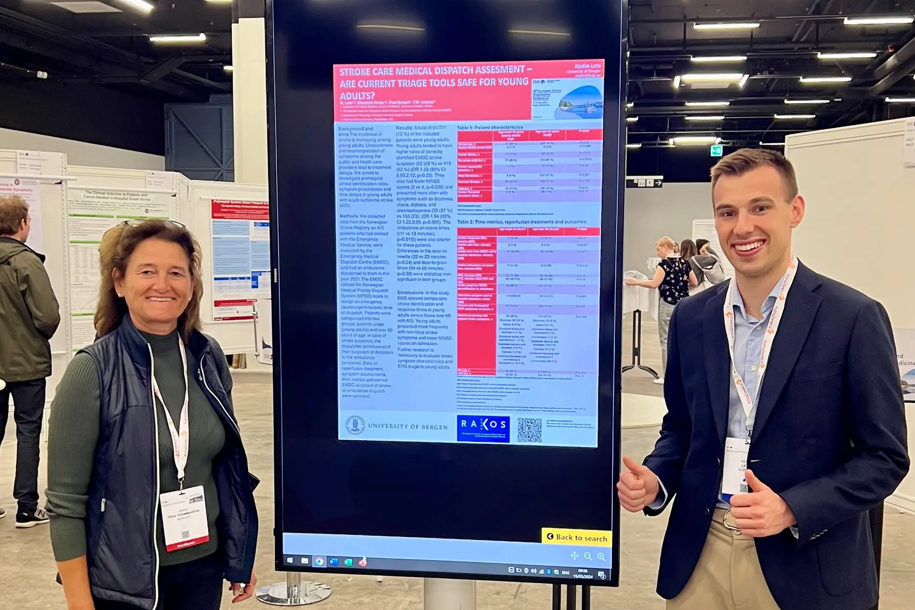 A man and a woman standing next to a large screen