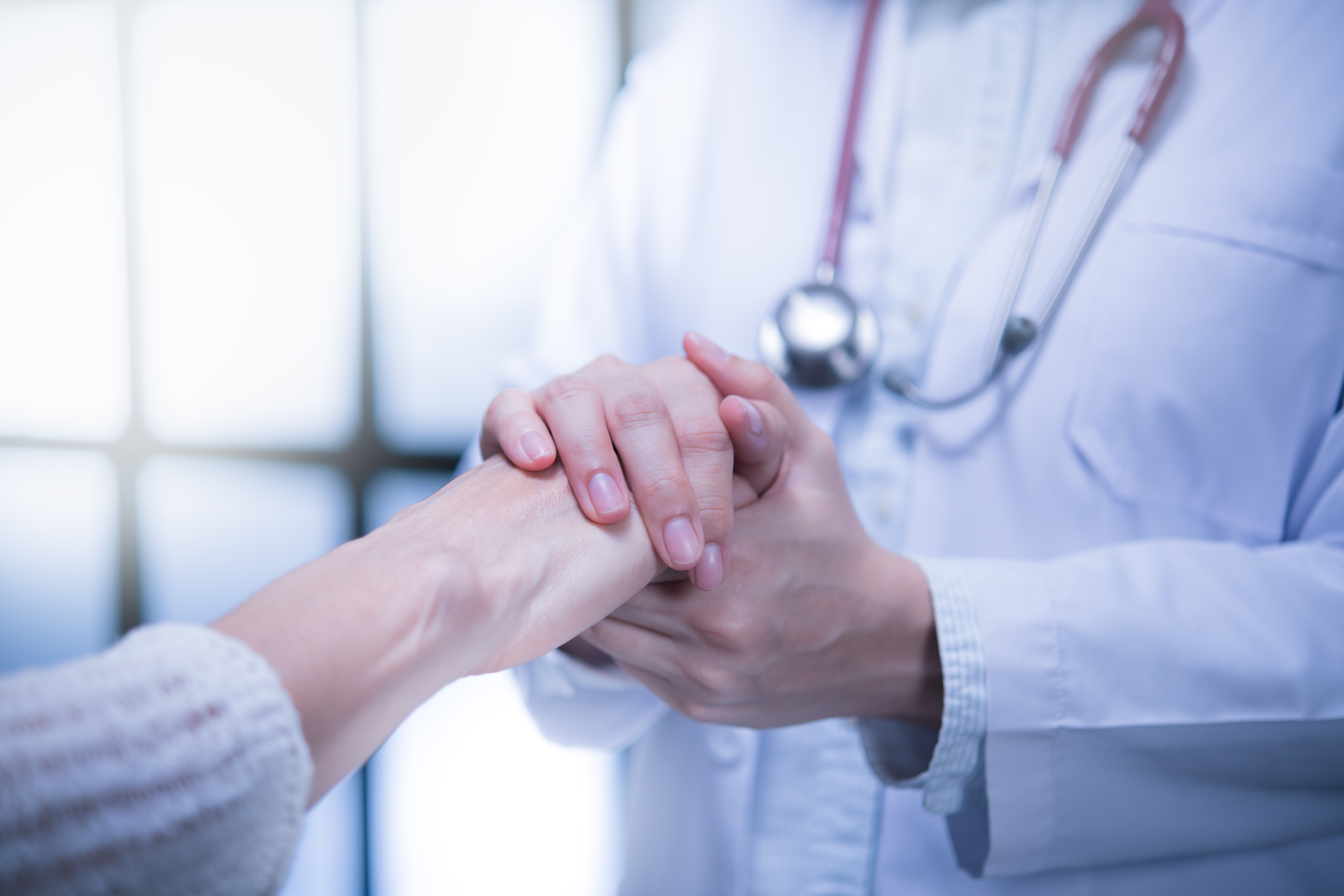 En lege som holder pasientens hender