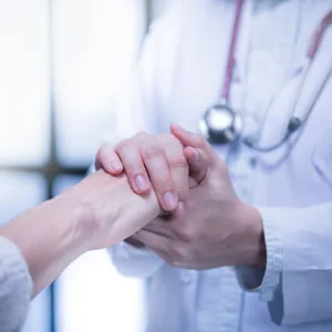 En lege som holder pasientens hender