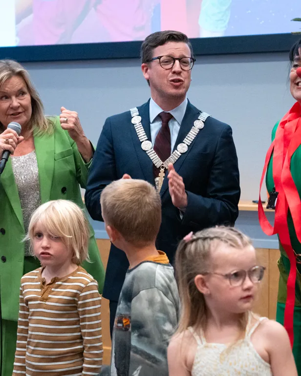 En person som snakker inn i en mikrofon med barn rundt seg