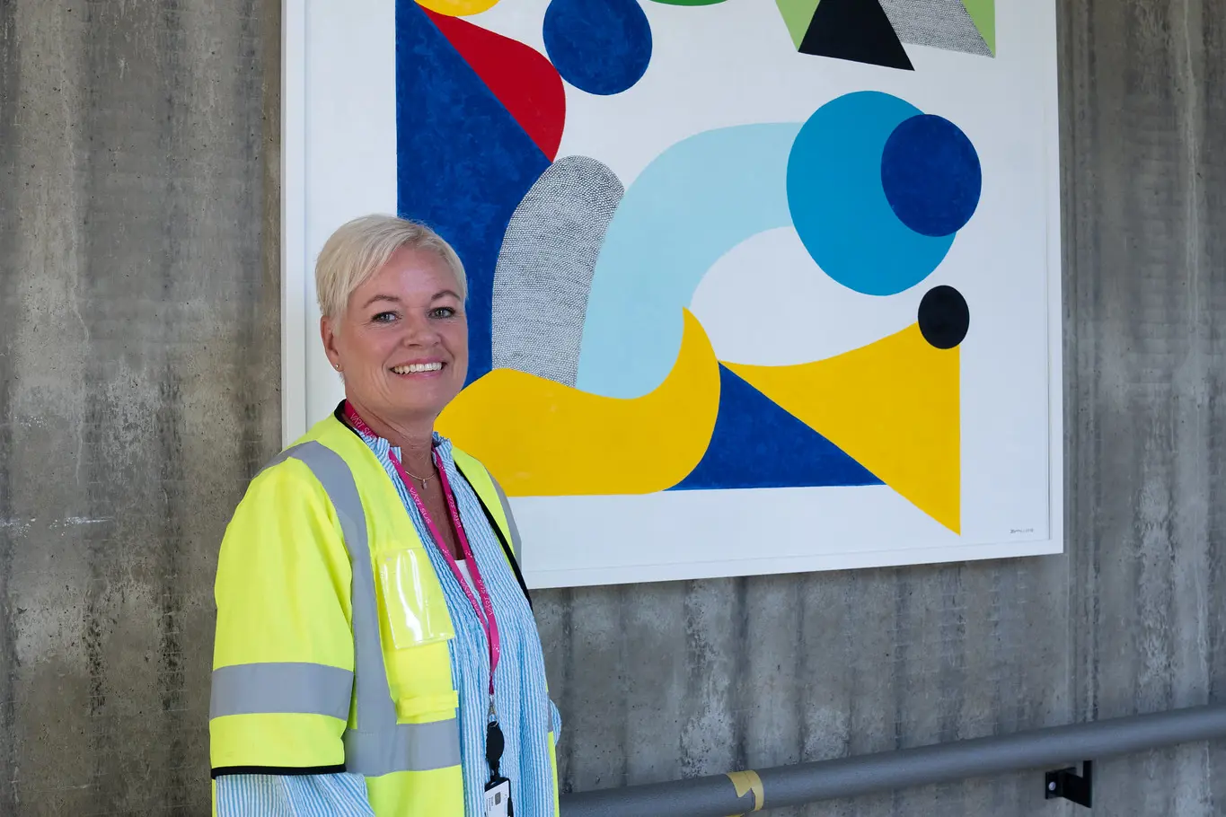 En person i sikkerhetsvest som står ved siden av et maleri