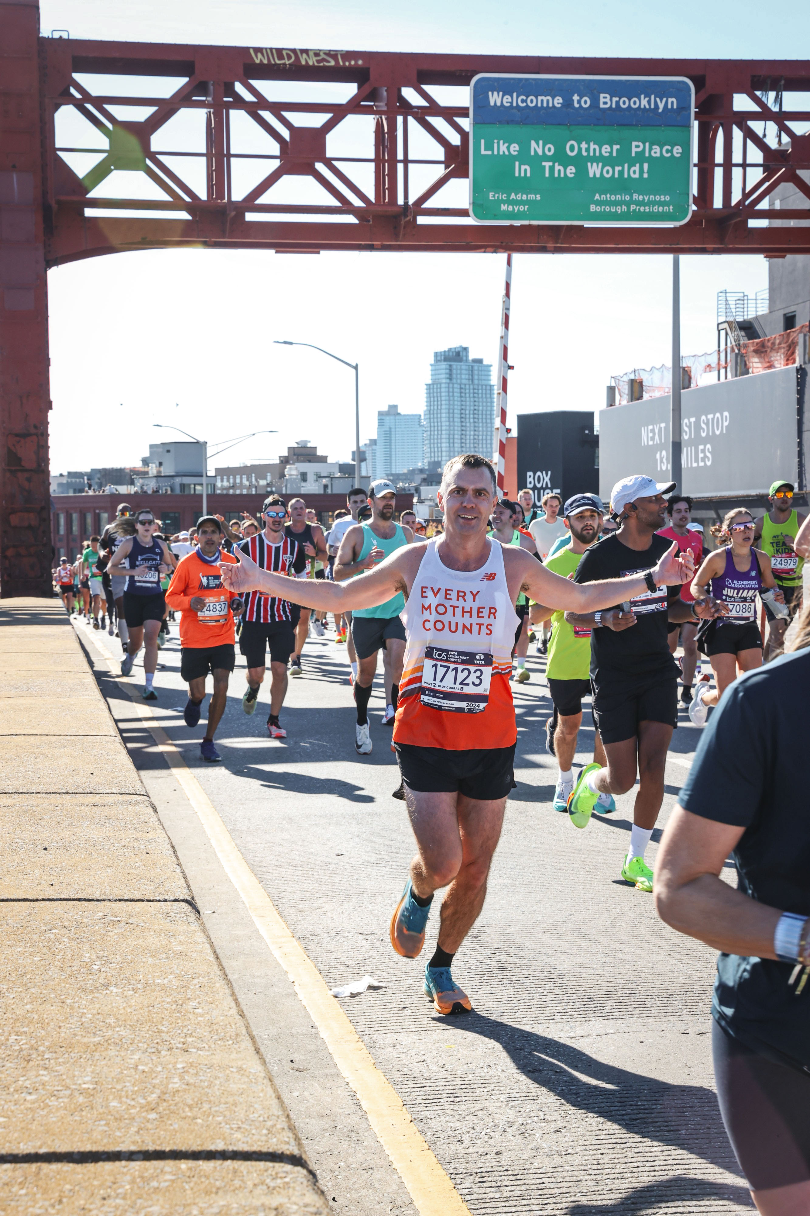 En gruppe mennesker som løper på en vei under en bro