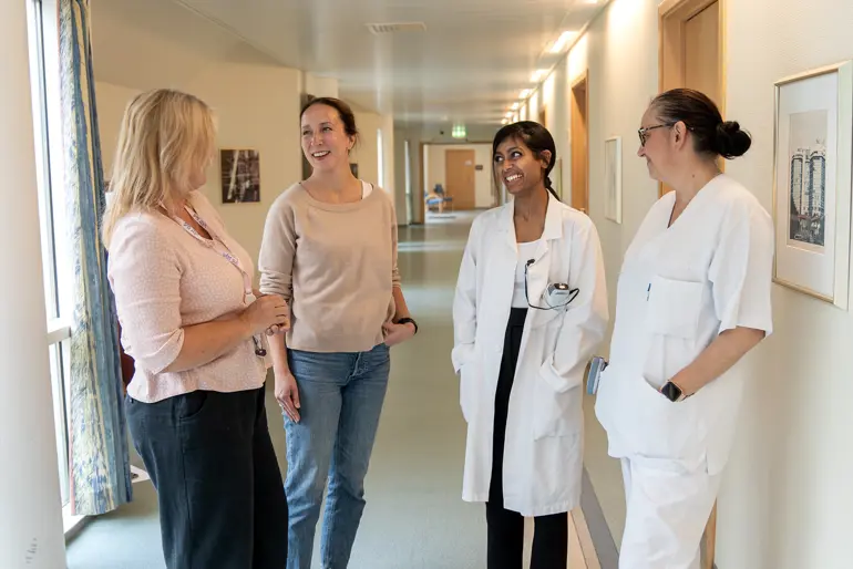 En gruppe mennesker i hvite laboratoriefrakker som står i en gang