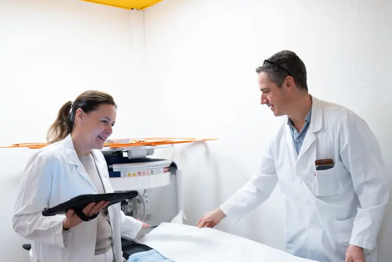 En mann og en kvinne i hvite laboratoriefrakker som ser på et nettbrett