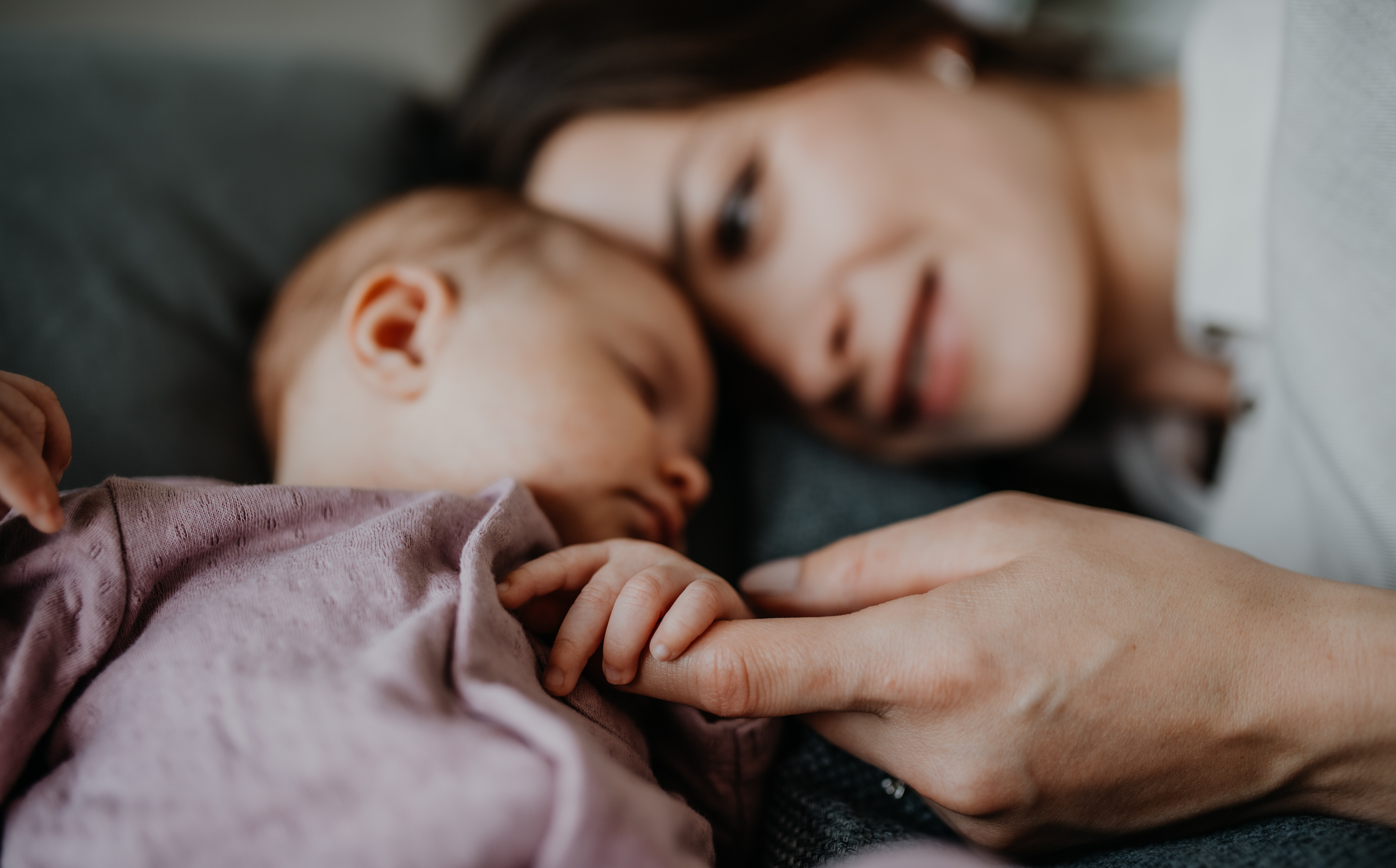 En kvinne som ligger ved siden av en sovende baby