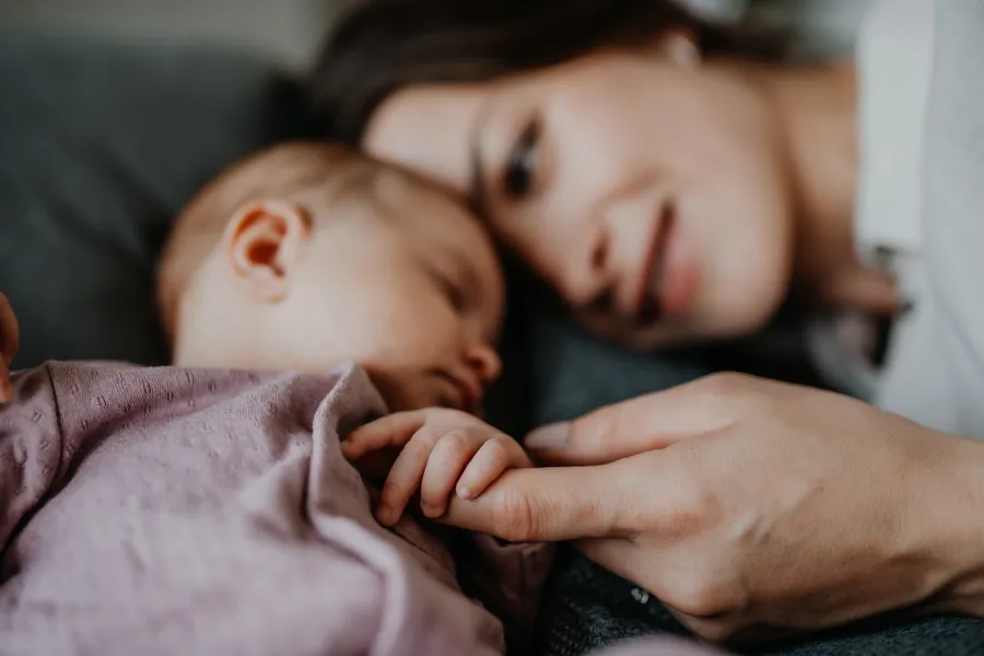 En kvinne som ligger ved siden av en sovende baby