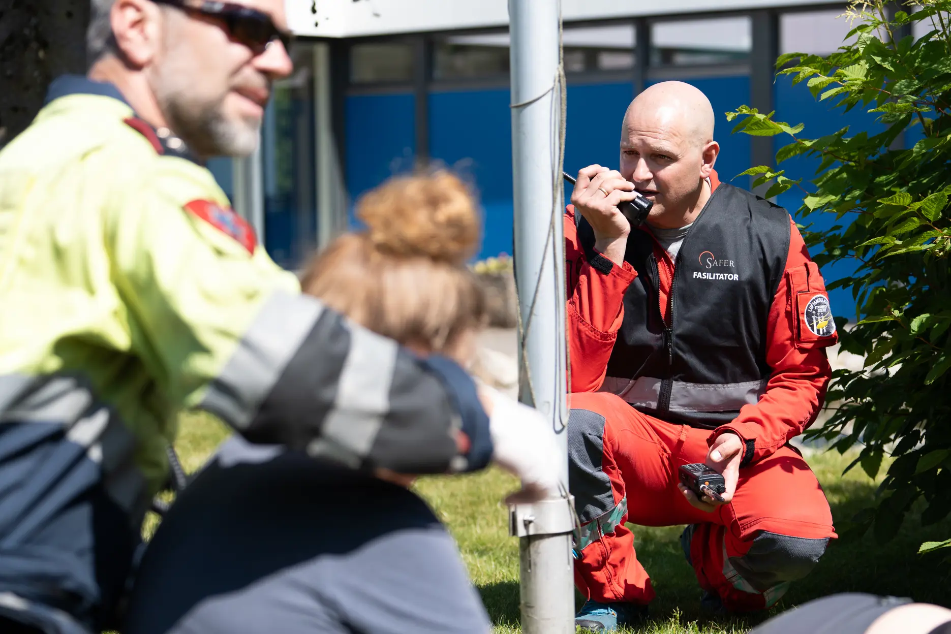 En mann i rød uniform snakker inn i en walkie talkie.