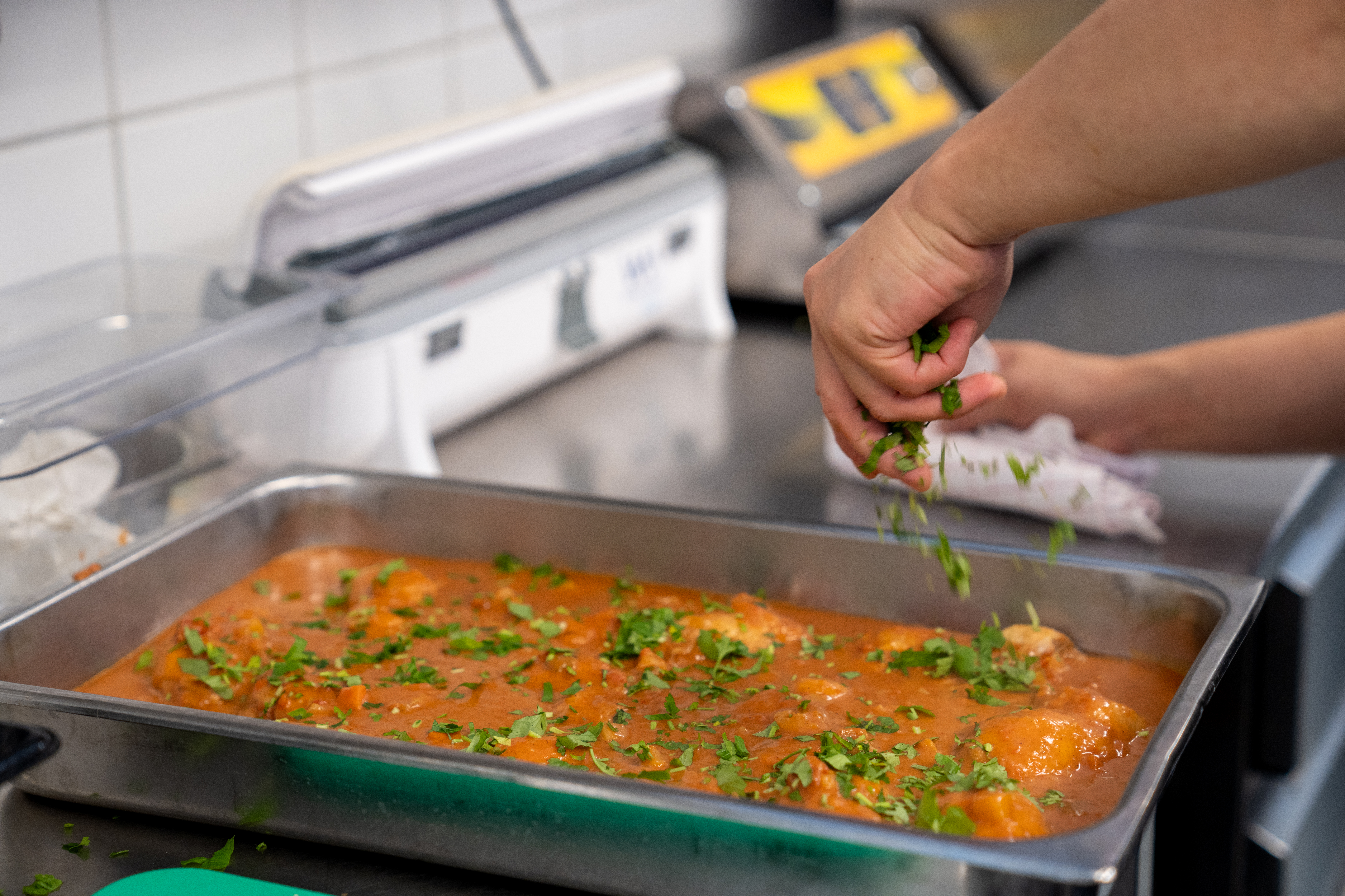 Hånd strør urter over mat