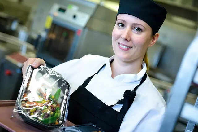En kokk holder opp en fargerik salat som er pakket inn i plast