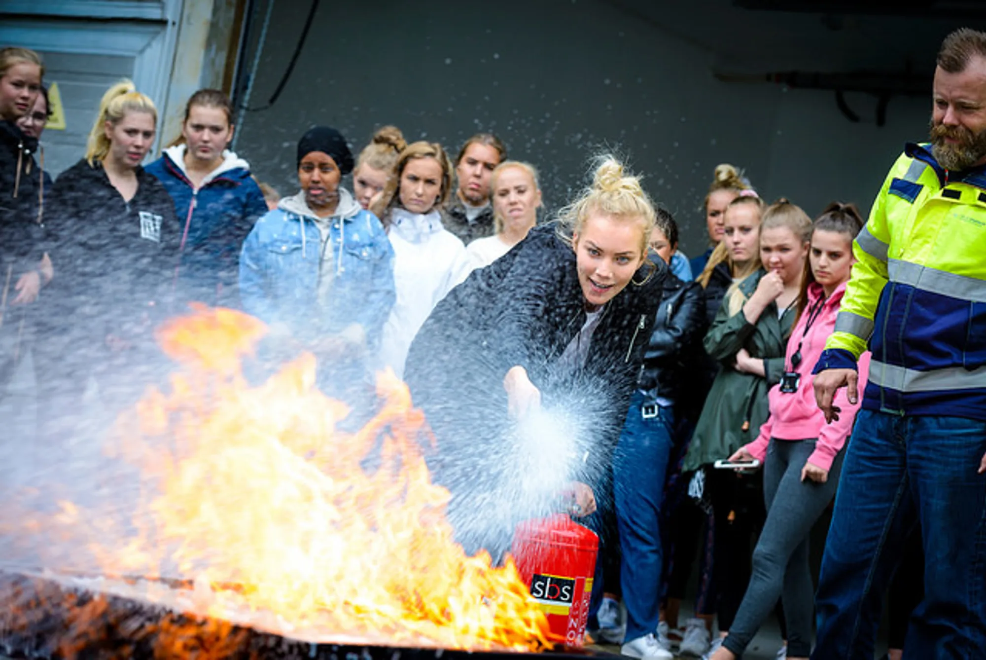 En lærling slukker brann med apparat mens de andre ser på foto .