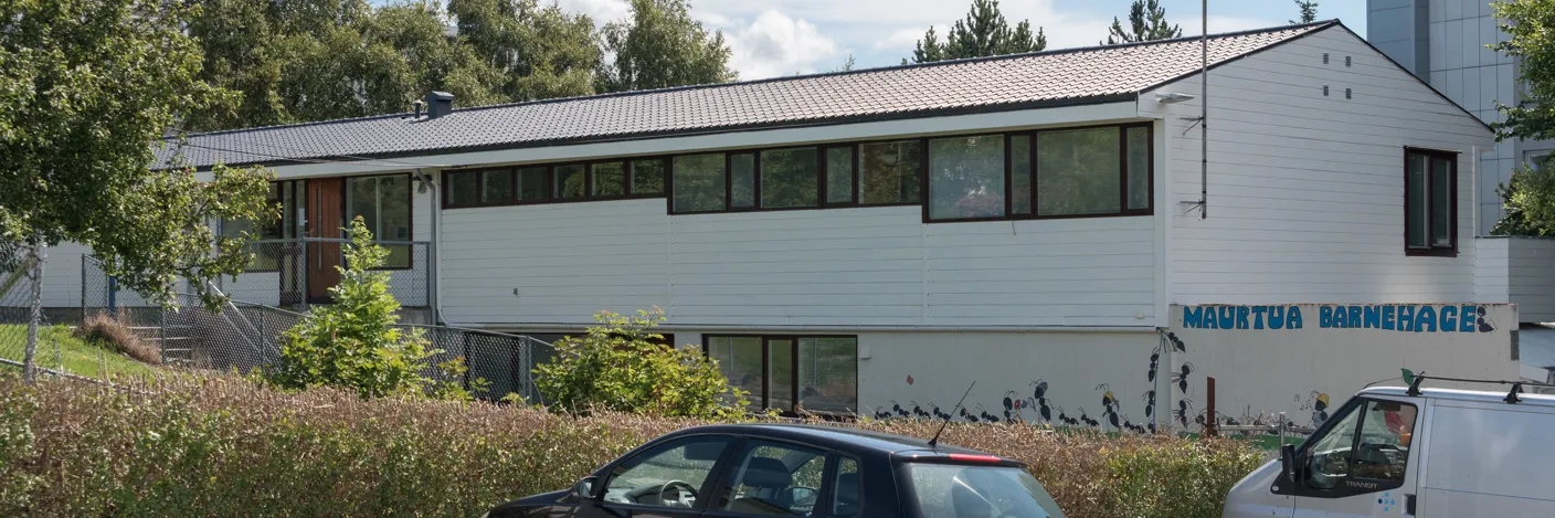 Hvit trebygning ved siden av internatet. Inngang på den ene langsiden av bygningen.