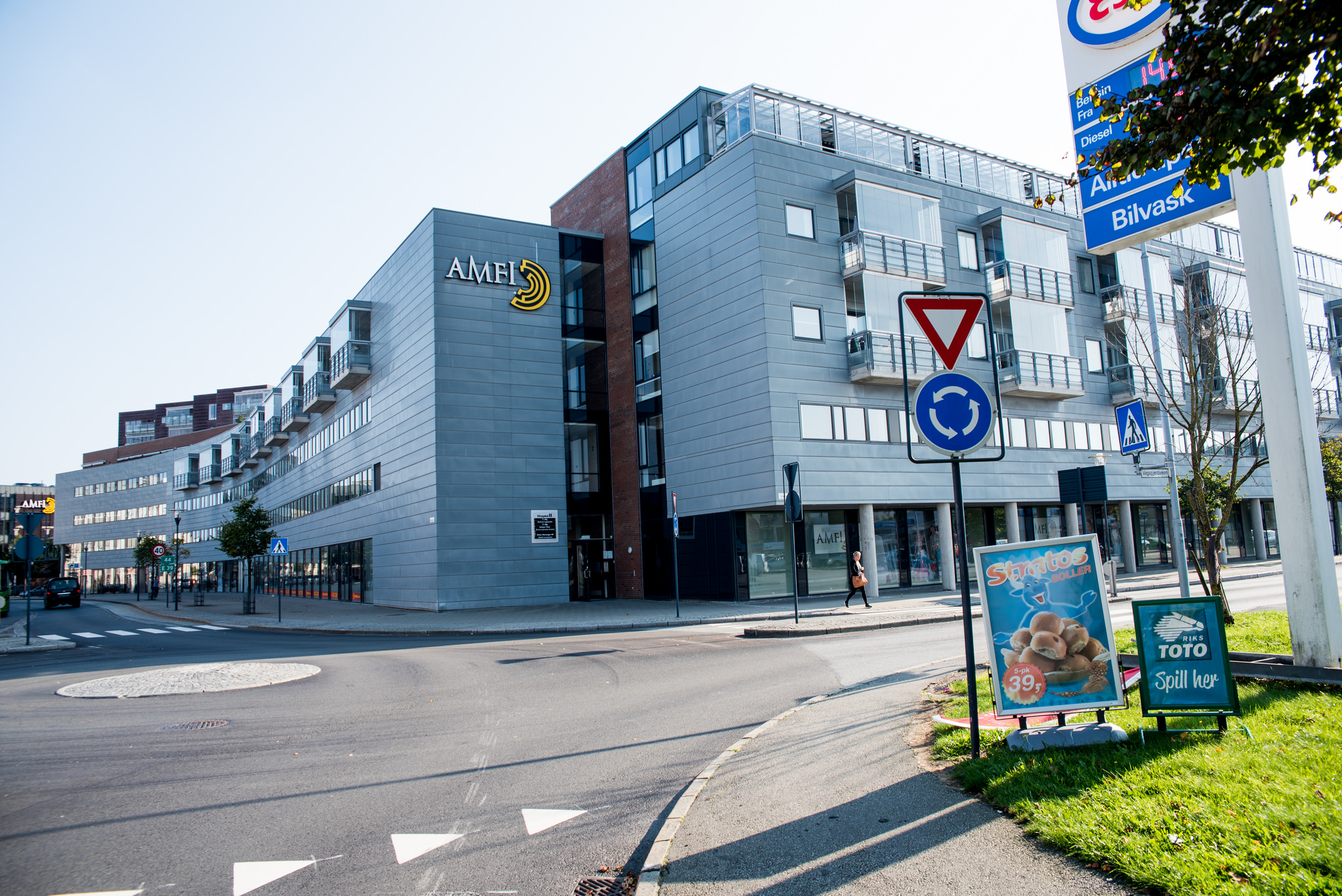 Grått bygg med vinduer og Amfi-skilt som ligger rett ved en rundkjøring.