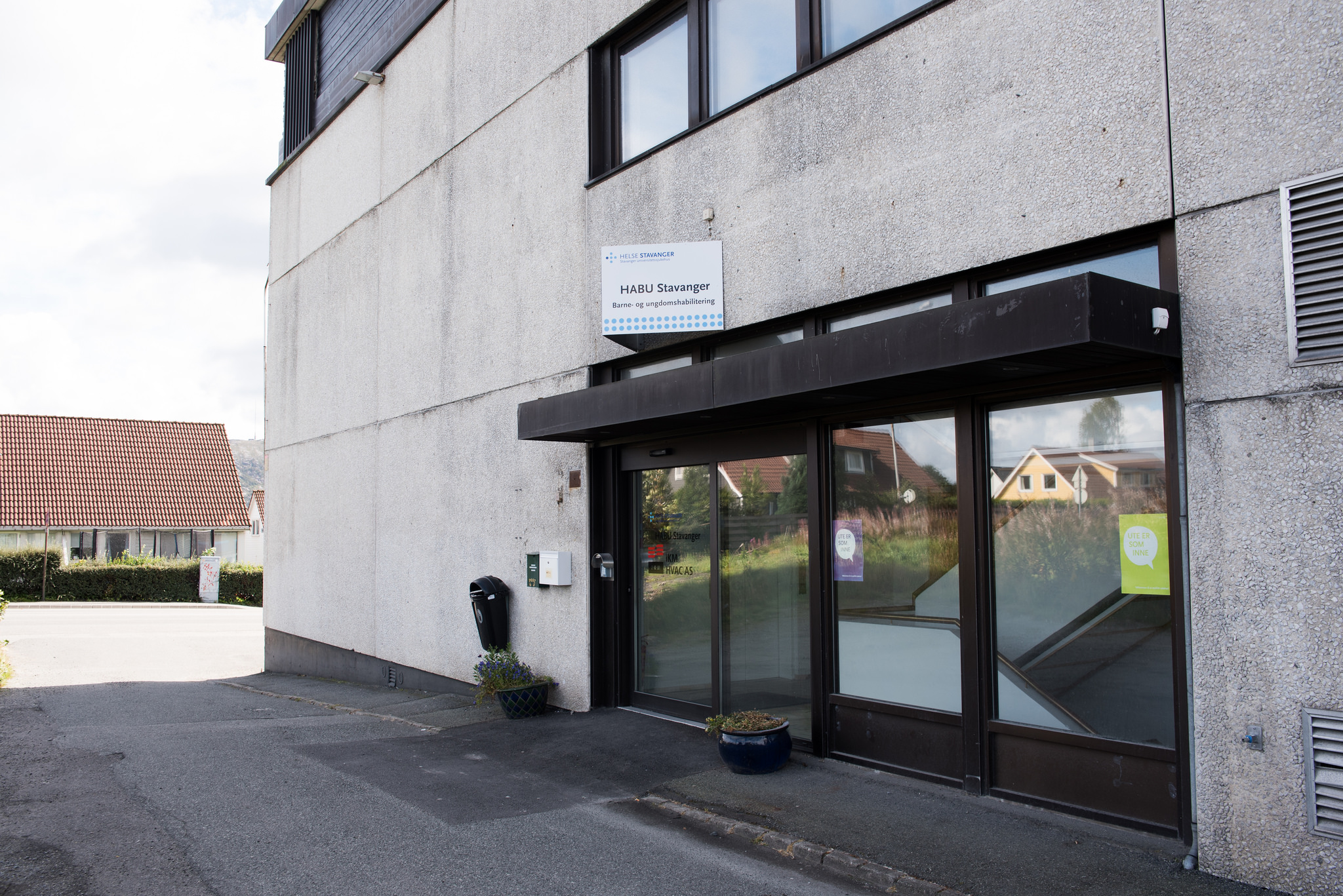 Grått murbygg med glassdører som inngang.