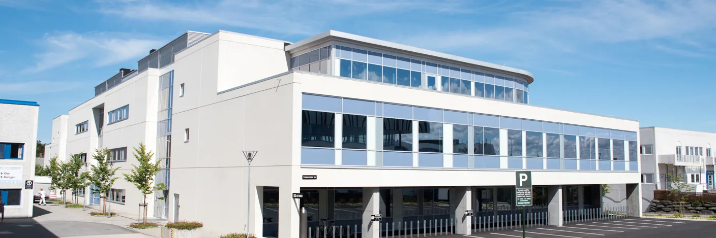 Murbygg med parkeringsplass. Foto.