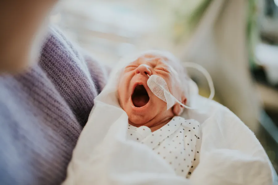 Nyfødt baby som gjesper. Bilde.