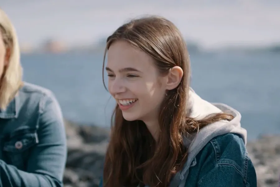 Ungdom ved kysten som smiler. Bilde.