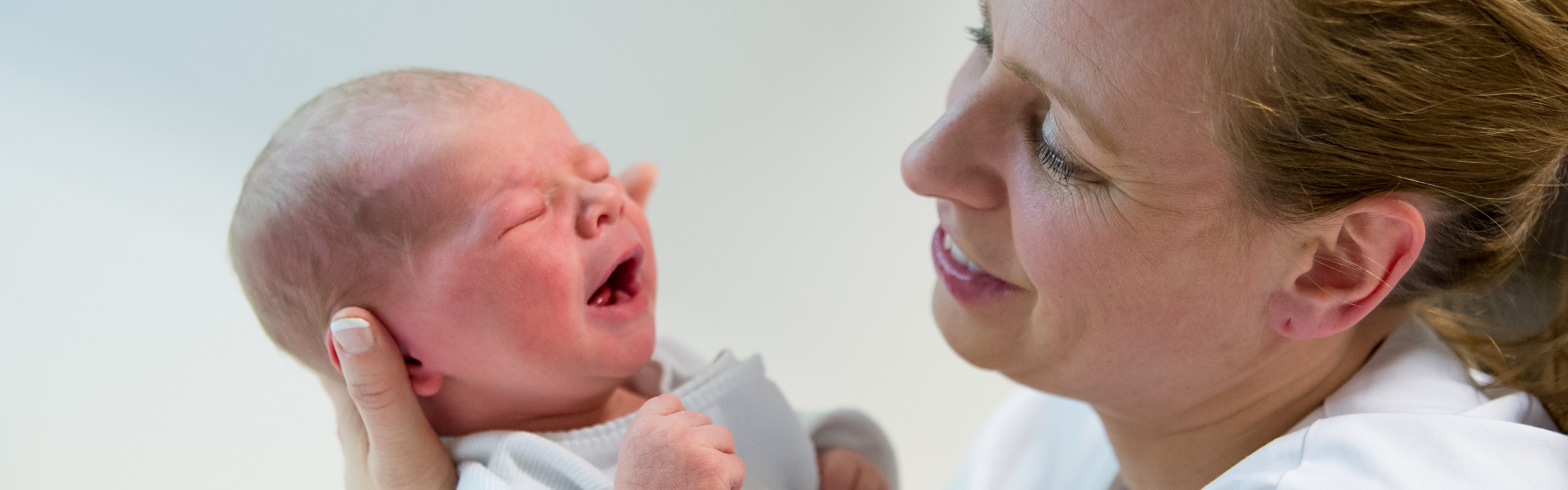 Nærbilde av jordmor som ser på en baby. Foto.
