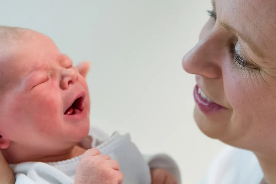 Nærbilde av jordmor som ser på en baby. Foto.