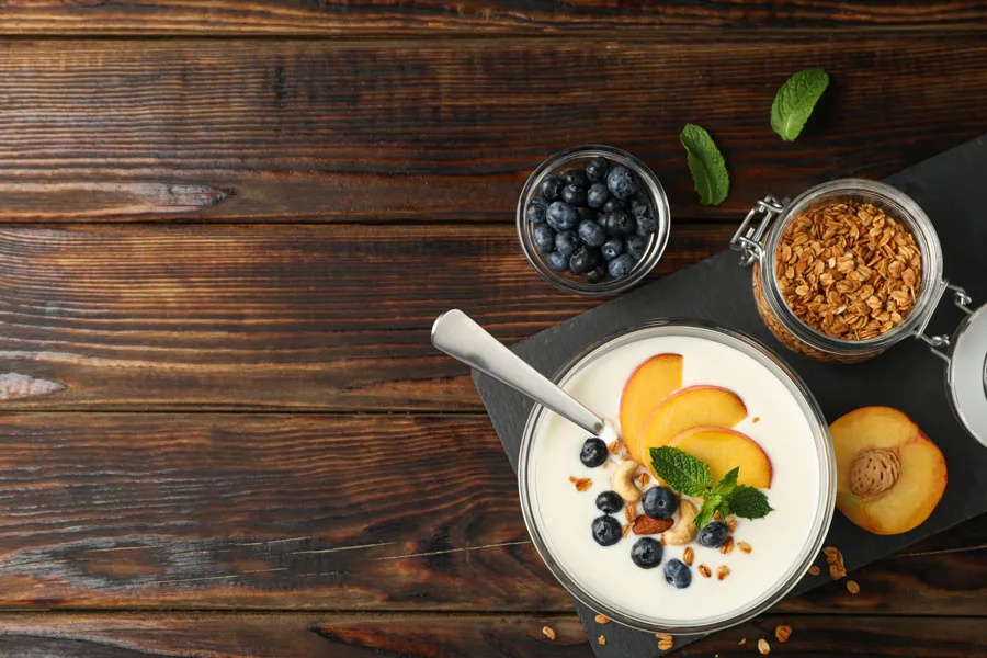 Yoghurt og gryn og frukt på et bord. Bilde.