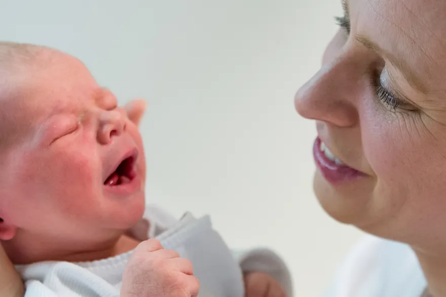 Nærbilde av jordmor som ser på en baby. Foto.