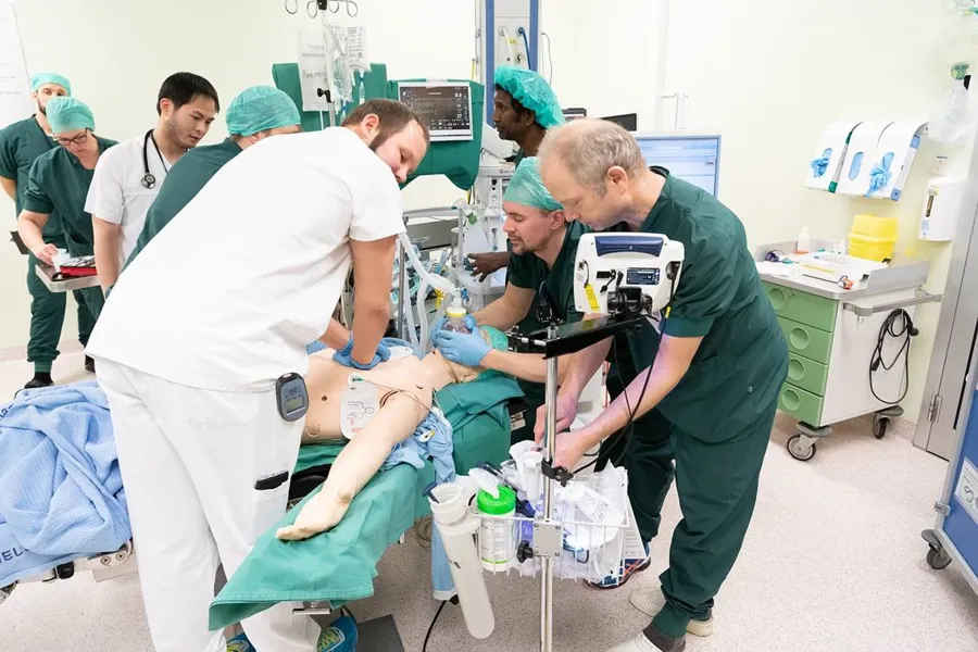 Simulering. Helsepersonell øver på å gi helsehjelp og står over en dukke. Foto.
