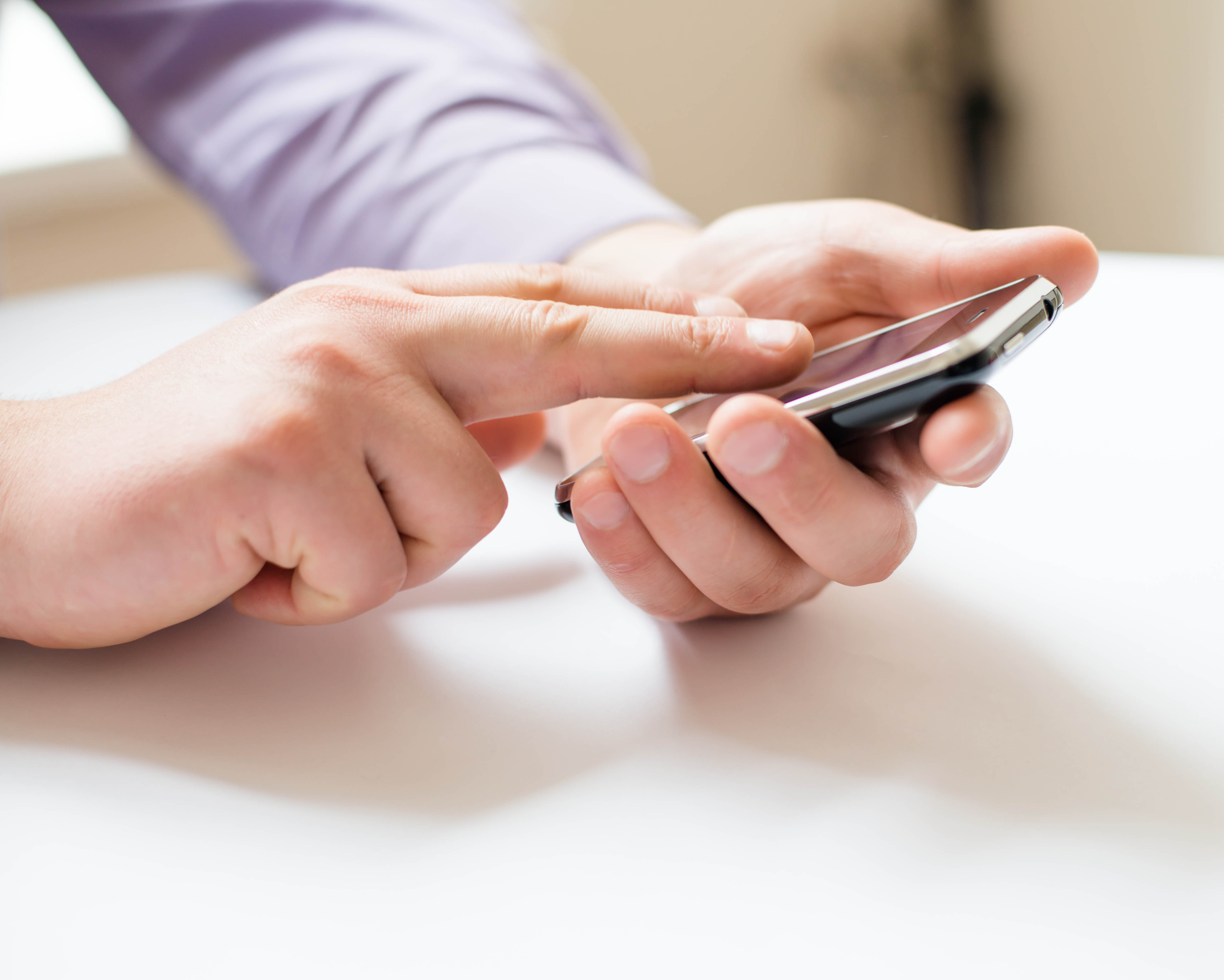 Mann som holder og skriver på en mobiltelefon. Foto.