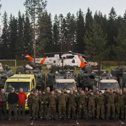 En gruppe mennesker som står foran et helikopter