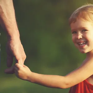 Jente som holder far i hånden og smiler. Foto.