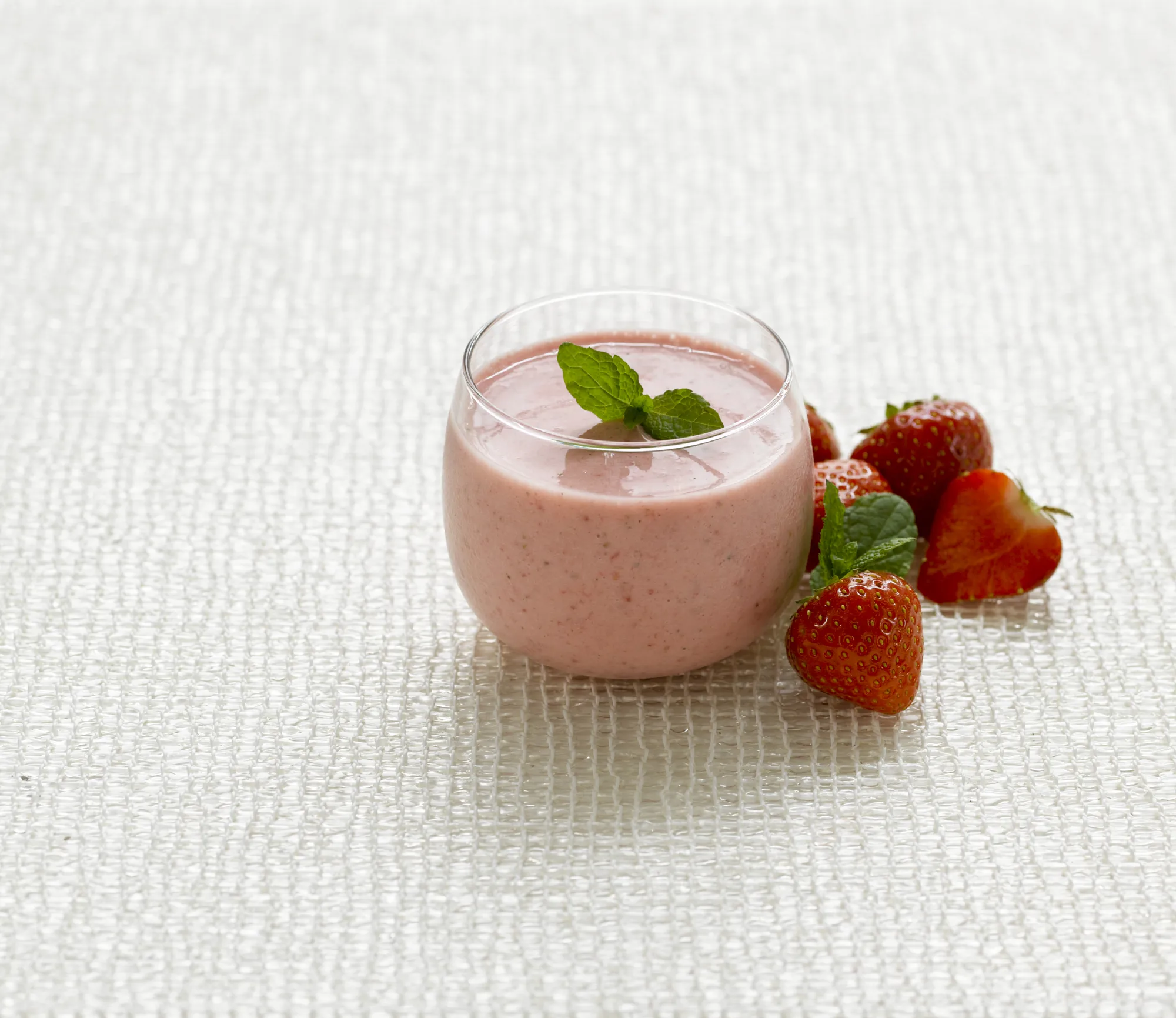 Et glass med yoghurt med jordbær ved siden av