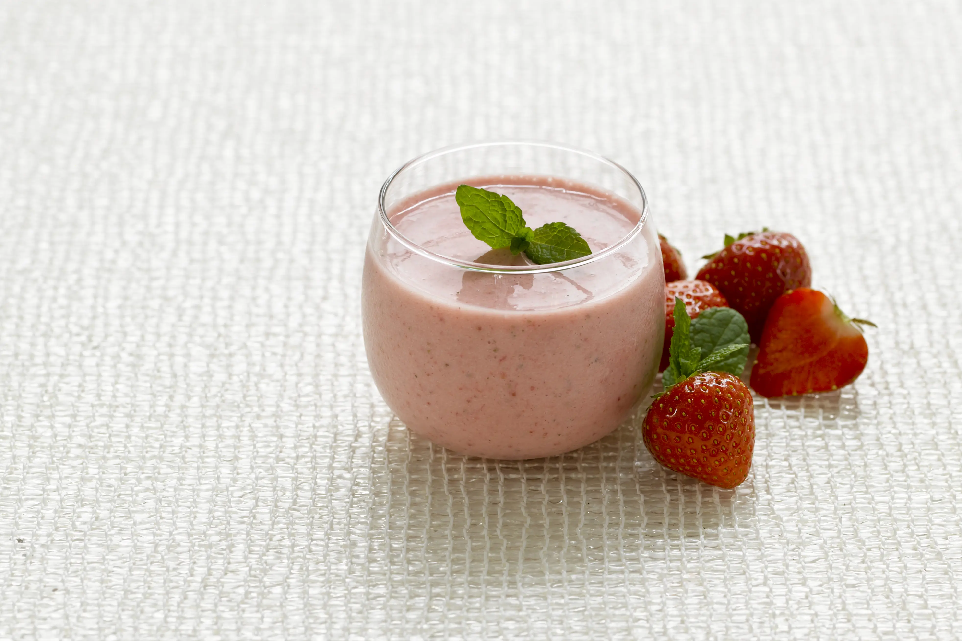Et glass med yoghurt med jordbær ved siden av