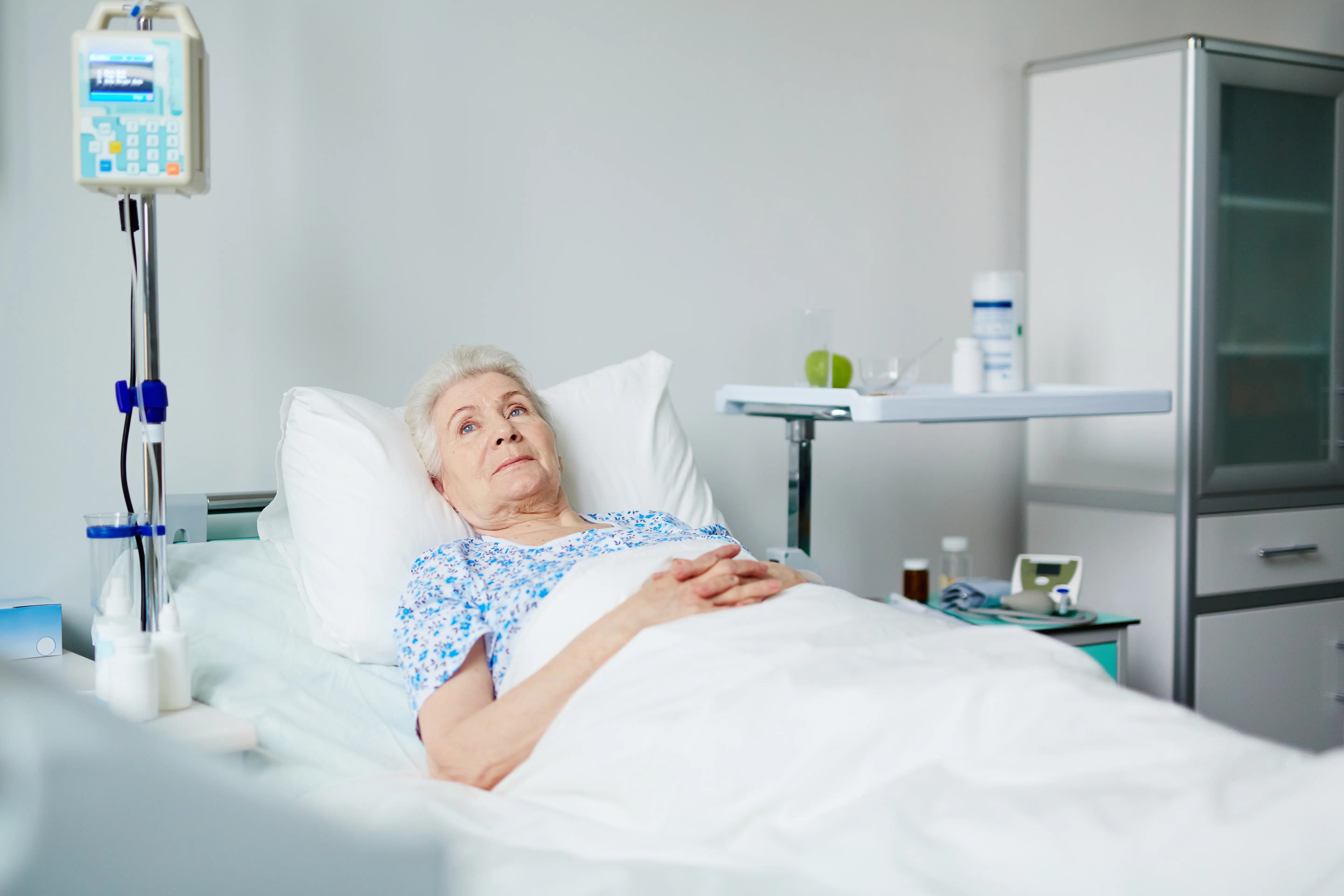 Eldre pasient ligger i en seng. Foto.