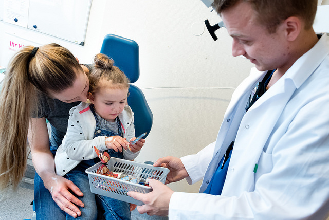 Barn på fanget til mor som får premie av lege. Foto.