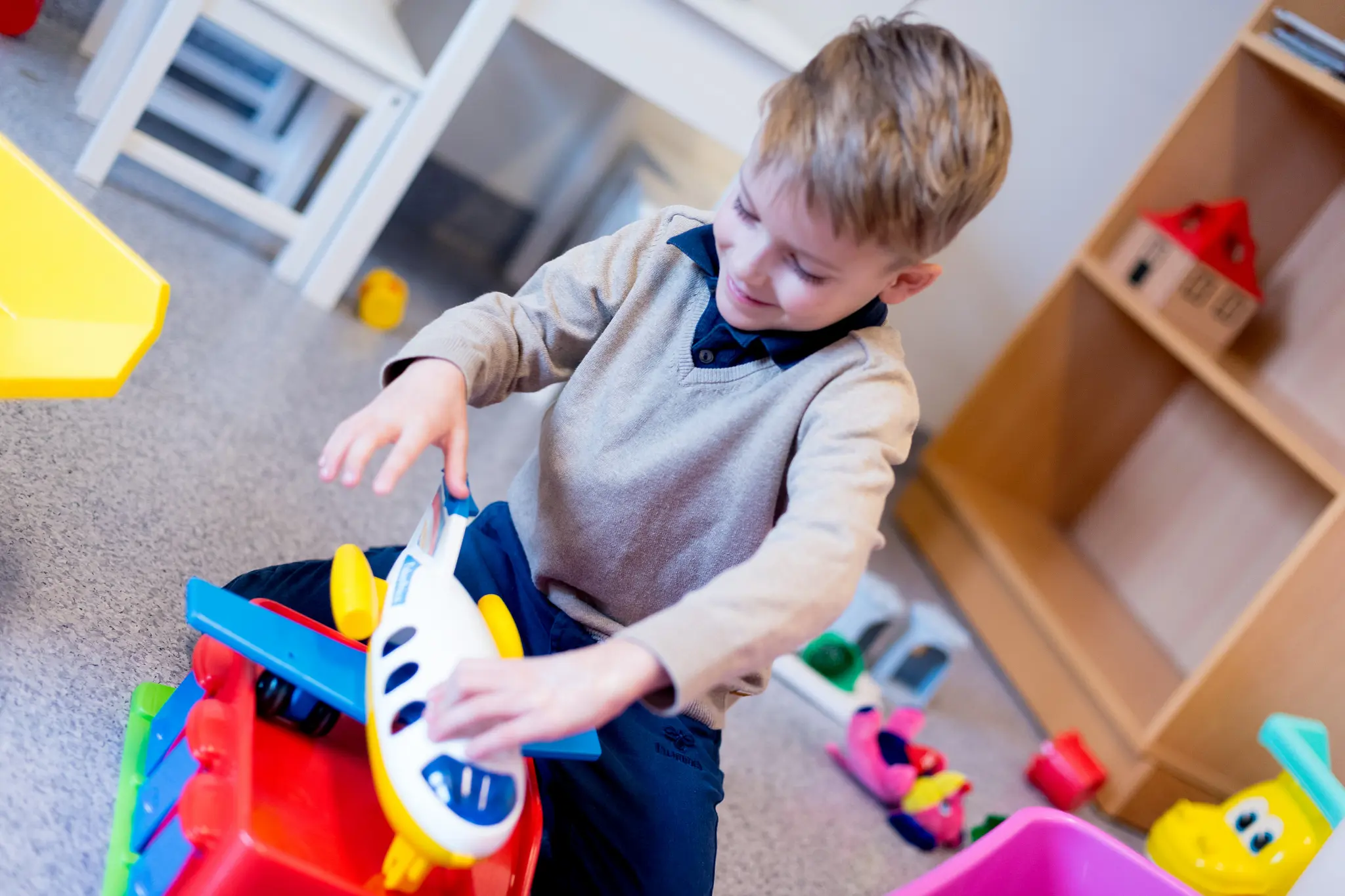 Gutt leker med et fly på et venterom. Foto.