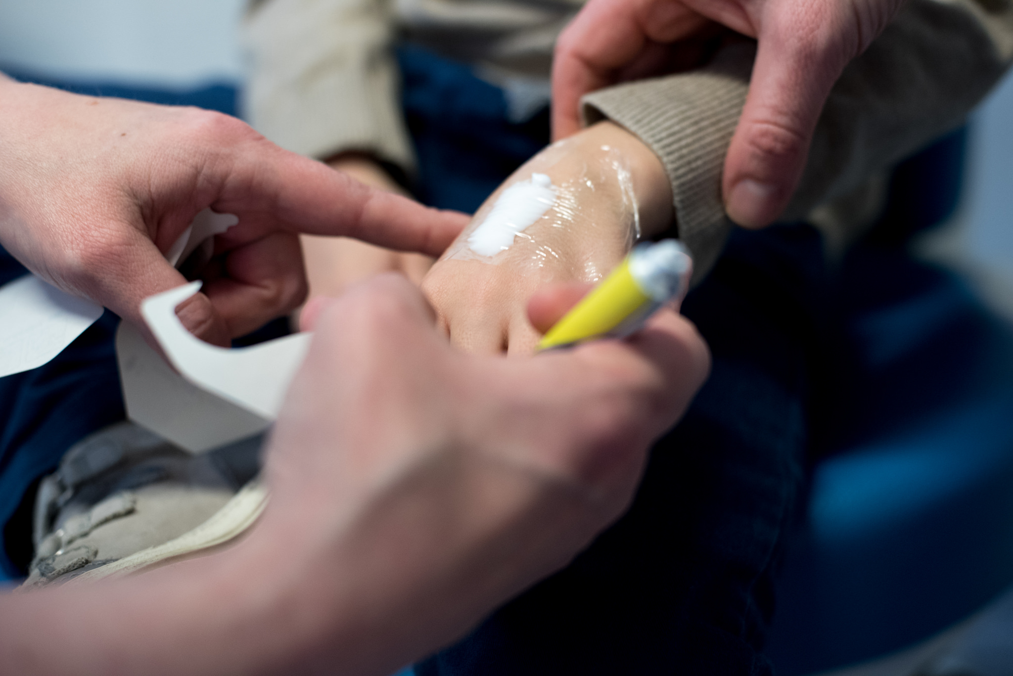 Barnehånd med plaster og voksne hender som holder barnehånden. Foto.